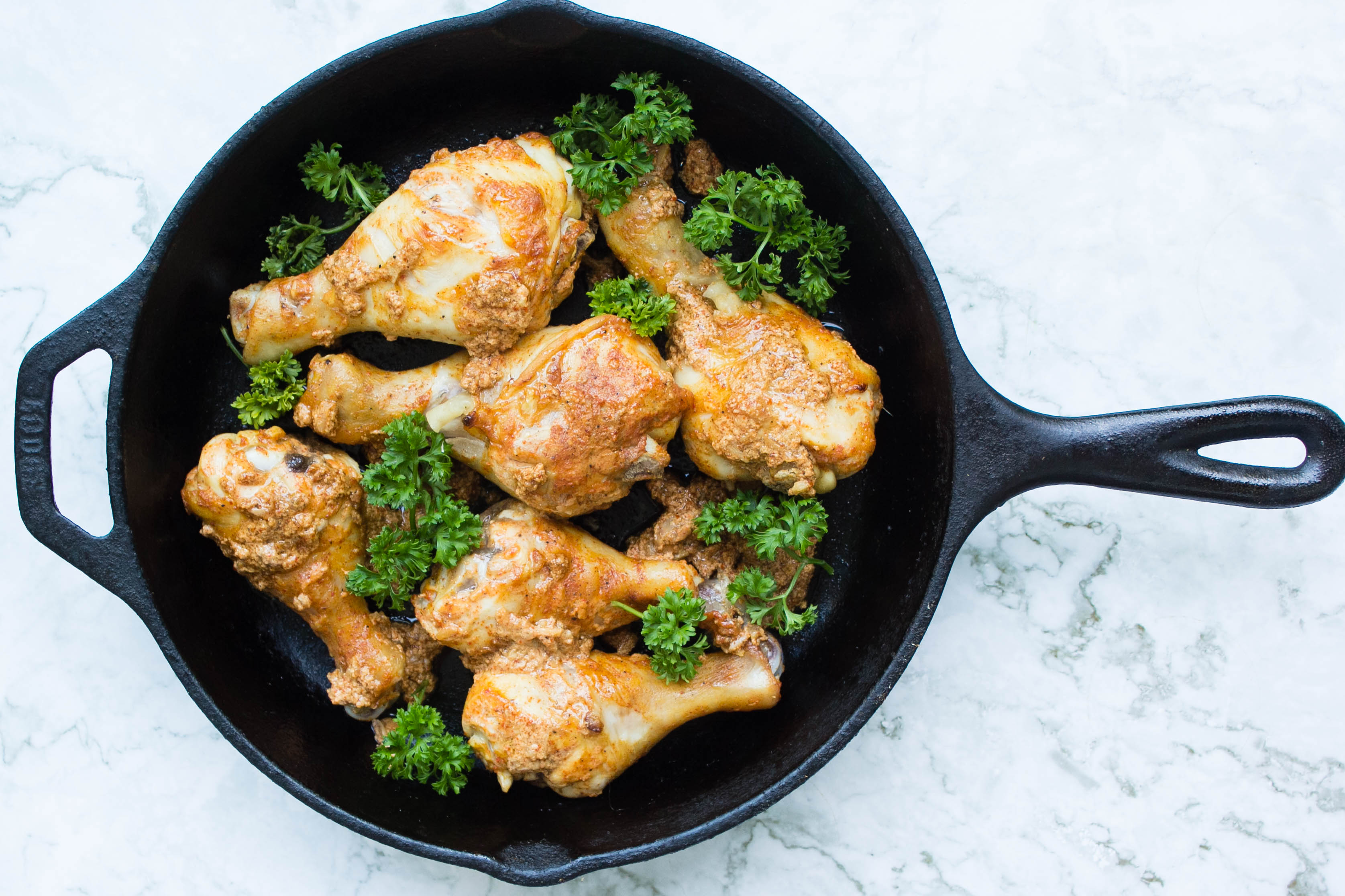 Pakistani chicken drumsticks in skillet with parsley garnish 