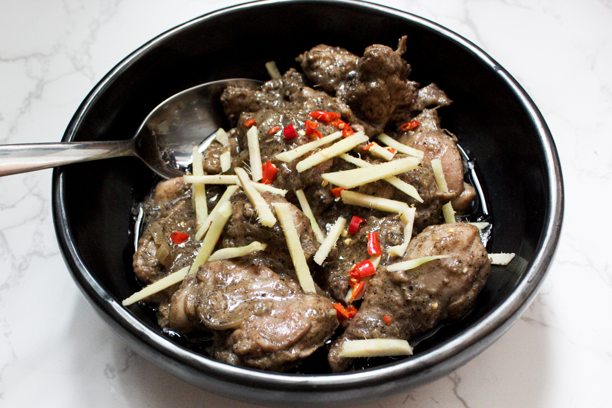 kali mirch chicken in a bowl with ginger and chili garnish 