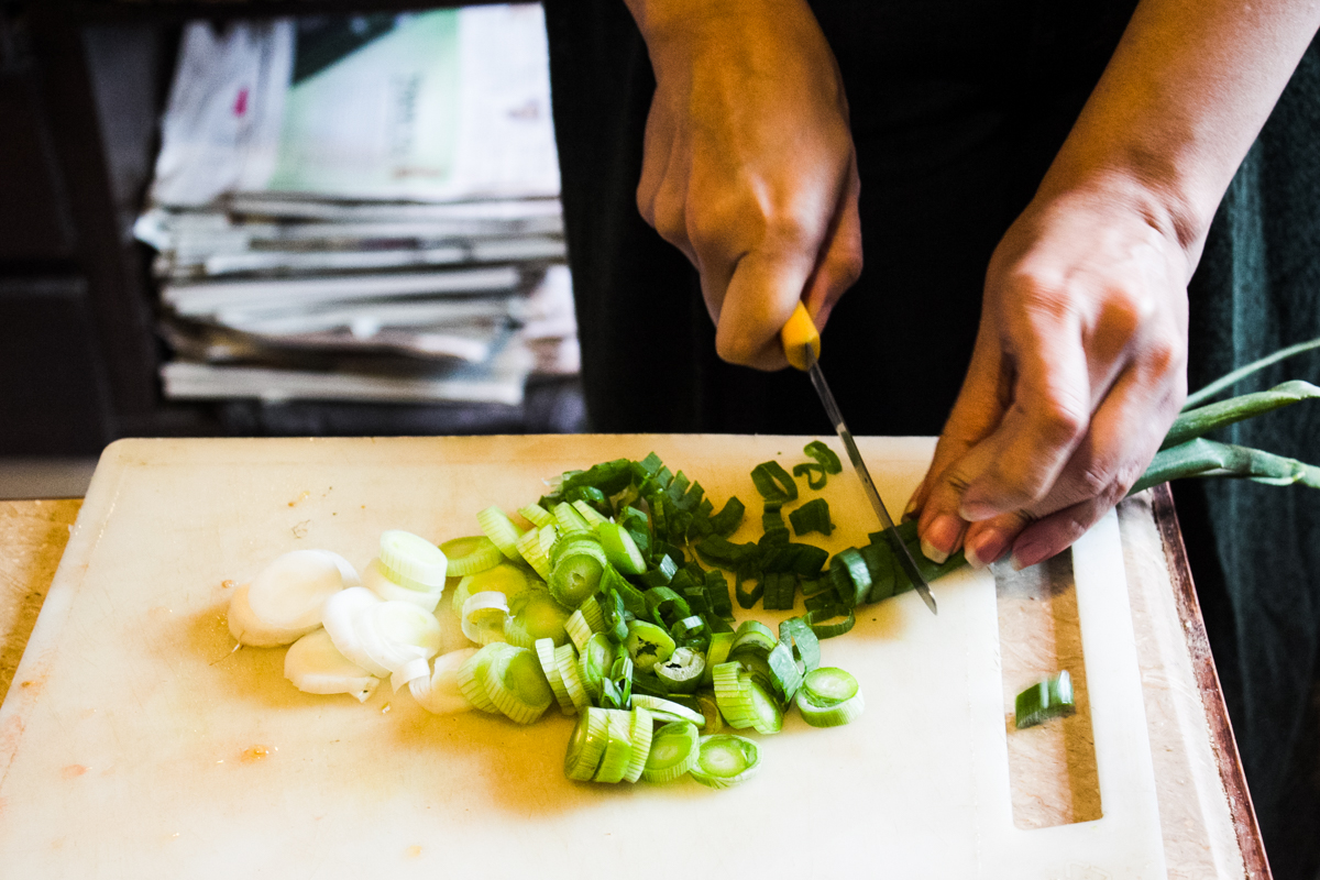 Young woman chopping spring onions crosswise