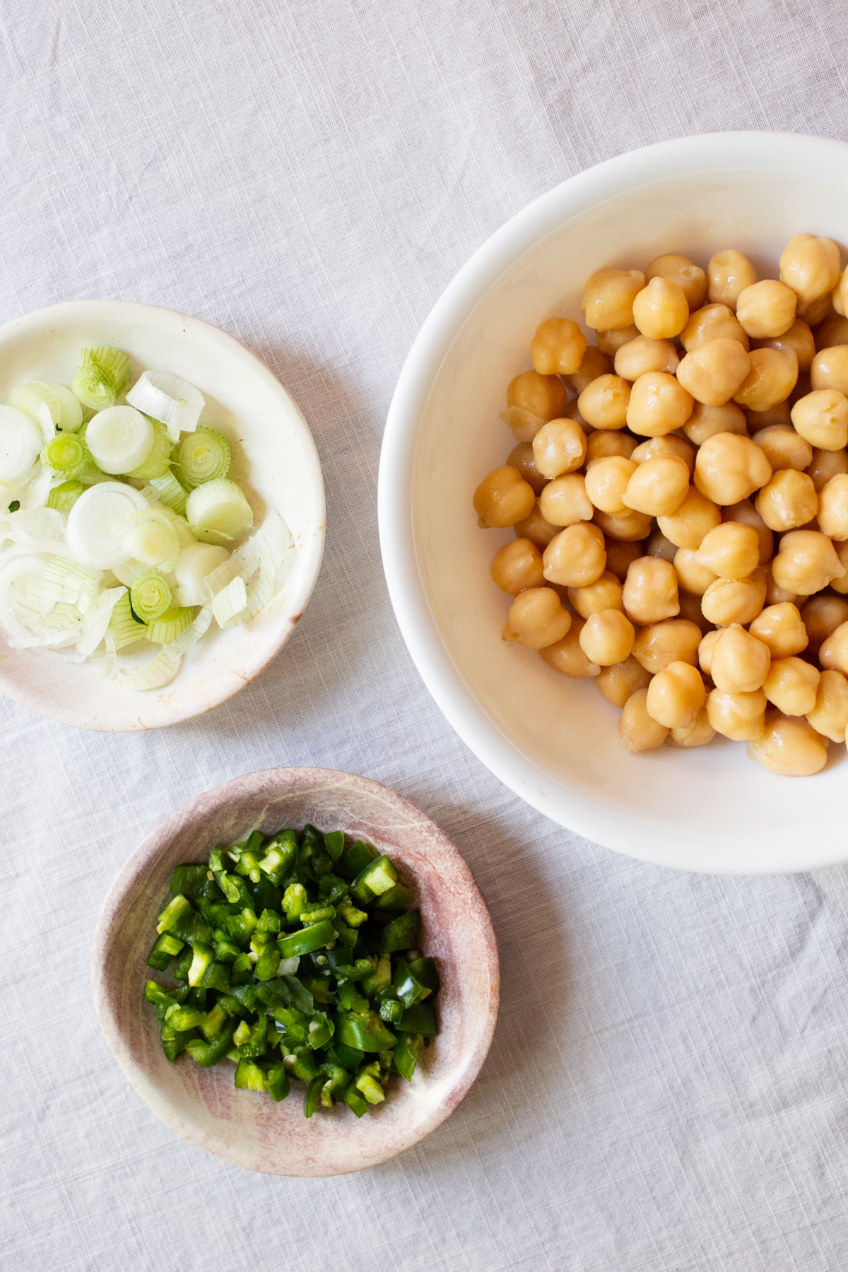 A bowl of drained chickpeas, chopped spring onions and green chlies